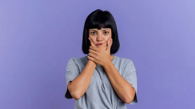 "Image: A girl touching her mouth, representing the fear of losing teeth in dreams related to financial concerns."